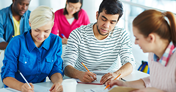 Studierendengruppe schreibt konzentriert an einem Tisch