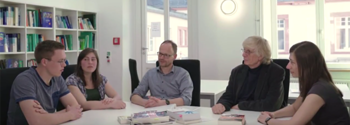 Bild: Menschen an einem Gruppentisch im Gespräch, auf dem Tischen liegen unterschiedliche Bücher