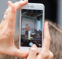 A lecturere is photographed with a smartphone.