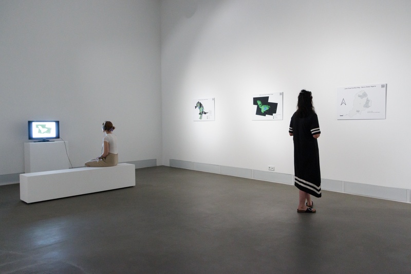 Ausstellungsraum mit Satellitenbildern und Video-Installation zur Schrumpfung des Tschadsees © Aron Endres