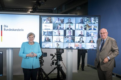You see Angela Merkel in front of a screen connected with the members of the Zukunftskommission Landwirtschaft