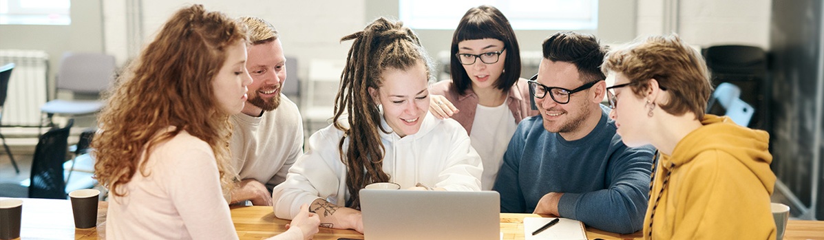 Banner Graduiertenzentren Mehrere junge Personen, die lächelnd zusammen auf einen Laptop schauen