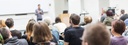 Bild: Lehrender vor einem Auditorium // Photo: Lecturer in front of a auditory