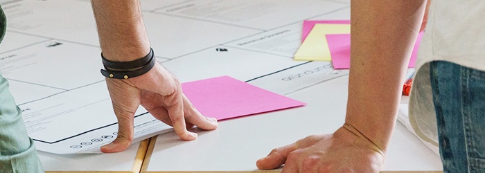 Bild: Ausschnitt zweier Personen, die vor einem Plan stehen (schmal) // Photo: Detail of two people standing in front of a plan