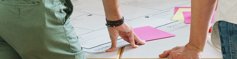 Bild: Ausschnitt zweier Personen, die vor einem Plan stehen // Photo: Detail of two people standing in front of a plan