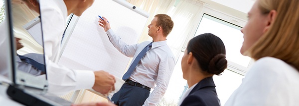 Bild: Junge Menschen in Businesskleidung, ein Mann schreibt an Flipchart // Photo: Young people in business clothes, a man writes to flip chart