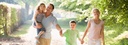 Bild: Familie mit zwei Kindern, die lachend einen Weg entlangläuft // Photo: Family with two children, walking along a path laughing