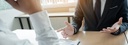 Bild: Blick auf Hände von zwei gegenübersitzenden Personen in Businesskleidung // Photo: View of the hands of two people sitting opposite each other in business clothing