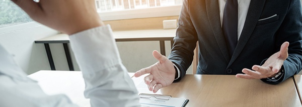 Bild: Blick auf Hände von zwei gegenübersitzenden Personen in Businesskleidung // Photo: View of the hands of two people sitting opposite each other in business clothing