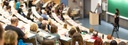 Bild: Blick in einen Hörsaal mit Studierenden und Dozent // Photo: View into a lecture hall with students and lecturer