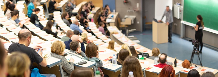 Bild: Blick in einen Hörsaal mit Studierenden und Dozent // Photo: View into a lecture hall with students and lecturer