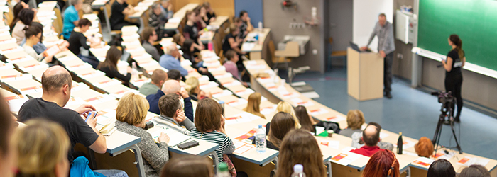 Bild: Blick in einen Hörsaal mit Studierenden und Dozent // Photo: View into a lecture hall with students and lecturer