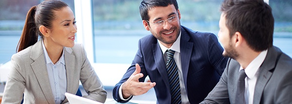 Bild: Eine Frau und zwei Männer in Businesskleidung unterhalten sich // Photo: A woman and two men in business clothes talking