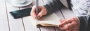 Bild: Ausschnitt einer Hand mit Kuli und Notizblock // Photo: Detail of a hand holding a pen and a notepad