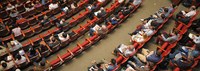 Bild: Banner der Konferenzsaal mit roten Stühlen und Menschen von oben zeigt // Photo: Banner showing people sitting in red chairs in a conference hall from a bird’s-eye view