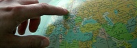 Bild: Zeigefinger, der auf ein Land auf einem Globus deutet // Photo: Forefinger pointing to a country on a globe