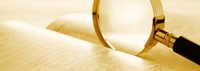 Bild: Ausschnitt einer Lupe auf einem Buch // Photo: Detail of a magnifying glass on a book