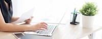 Bild: Person sitzt am Schreibtisch und überträgt Informationen von einem Blatt Papier in einen Rechner | Quelle: colourbox.com #249696