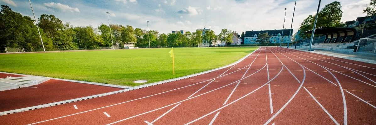 Schmuckgrafik: Die Tartanbahn und der dahinterliegende Rasenplatz des Sportstadions. 