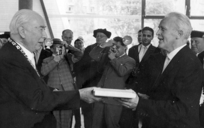 Geschenkübergabe zwischen Bundespräsident Theodor Heuss (links) und Bibliotheksdirektor Josef Schawe (rechts) anlässlich der Einweihung der Universitätsbibliothek in der Bismarckstraße 37 im Jahr 1959.