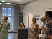 Vitrine mit Maskottchen "Seneca" und Ausstellungsbesucher