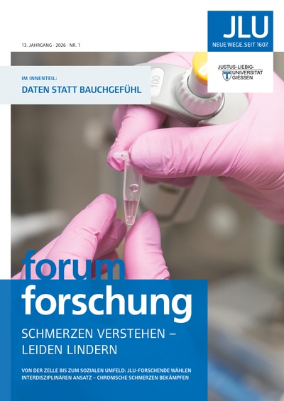 Titelseite des forum forschung Ausgabe 1/2026 mit der Abbildung von 2 Händen rosafarbenen Einmalhandschuhen, die in einer Laborumgebung ein kleines Gefäß mit durchsichtiger Flüssigkeit halten.