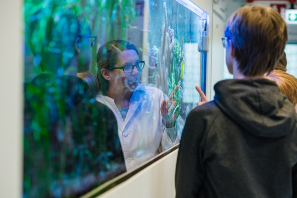 Wissenschaftskommunikation Aquarium Wissenschaftlerin zeigt auf Auquarium