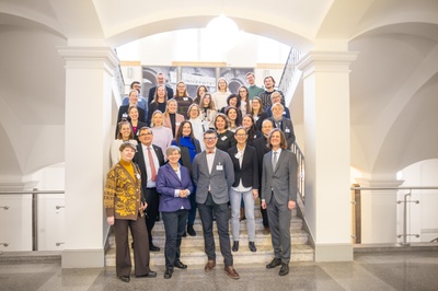 Gruppenbild mti ca. 20 Personen auf einer Treppe in einem hellen Gebäude. 