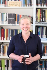 Prof. Milja Kurki in dunkler Bluse vor einem Bücherregal.