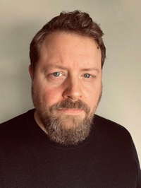Dr. Stefan Pedersen im dunklen Pullover vor neutraler Wand