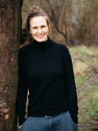 Sophie von Redecker im schwarzen Pullover neben einem Baum.