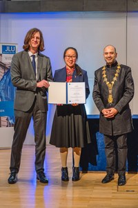 Yee Cheng Foo (Mitte) ist beim Akademischen Festakt der JLU mit dem DAAD-Preis ausgezeichnet worden. Die Auszeichnung wurde ihr von Vizepräsident Prof. Dr. Alexander Goesmann (links) und Präsident Prof. Dr. Joybrato Mukherjee (rechts) überreicht. Foto: JLU / Roland Duss