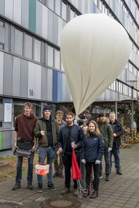 Das Projektteam aus Studierenden und Forschenden des II. Physikalischen Instituts mit dem Ballon und der orangefarbenen Sonde. Foto: Hartmut Schotte