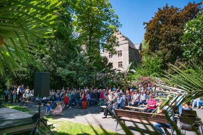Viele Zuschauer sitzen im Botanische Garten bei einer Veranstaltung der JLU zu „Kultur im Garten“