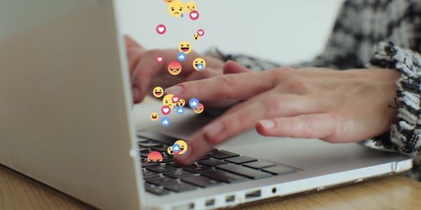 Kachel Netiquette Schmuckbild: Laptop, aus dem traurige, wütende und fröhliche Emoji-Symbole kommen