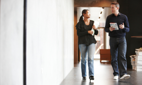 Two young research assistants walking through a hallway, in conversation