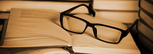 Photo: Black glasses lying on a pile of books