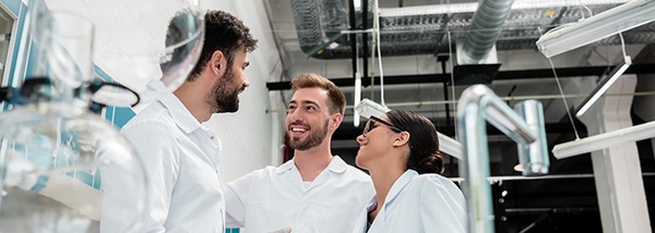 Photo: Two men and a woman in white coats talking in a lab