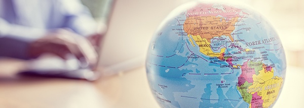 Photo: Globe with person at the laptop in the background