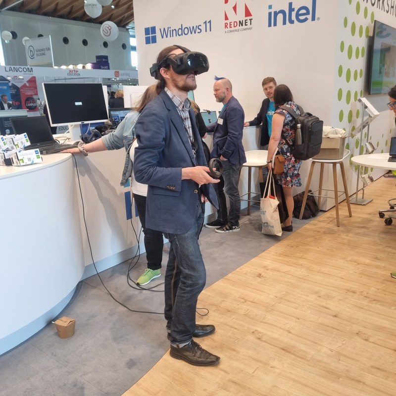 Man with vr glasses, trade fair stands in the background