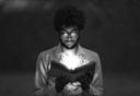 Male person holding an open book in their hands. A bright light appears to emanate from the book. The person is looking at the book intently.